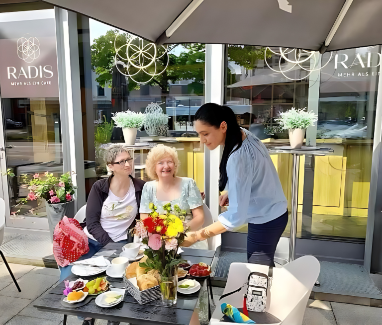 Die Café Besitzerin Radmila bedient zwei Gäste auf der Terrasse des Cafés.